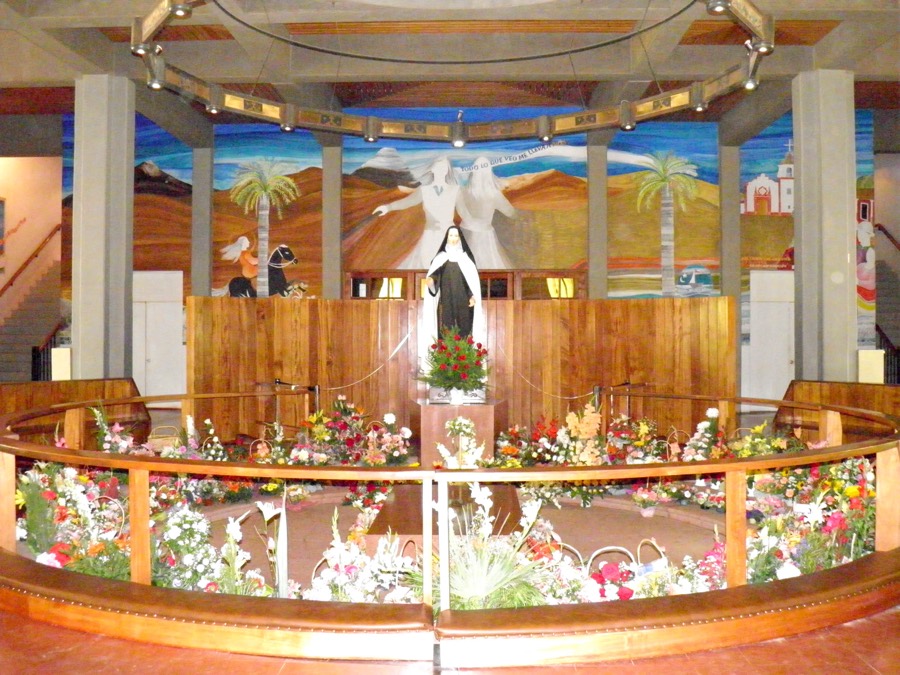 Interior de la cripta: murales y flores alrededor de la tumba de la santa